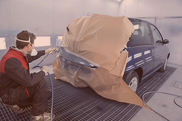 auto technician painting an automobile after a car accident